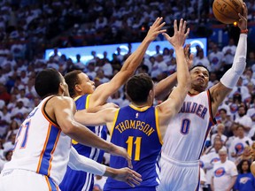 Oklahoma City Thunder guard Russell Westbrook goes after a loose ball against Golden State Warriors guard Stephen Curry and guard Klay Thompson. (AP Photo/Sue Ogrocki)