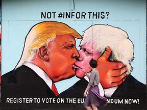 A passerby views a mural showing likely U.S. Republican presidential nominee Donald Trump (L) kissing the Former Mayor of London and Conservative MP, Boris Johnson, on the side of a building in Bristol, south west England on May 24, 2016. (AFP PHOTO/GEOFF CADDICK)