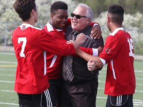 Coach John Sikora is flanked by players after winning the senior boys premier division city soccer title in Sudbury, Ont. on Wednesday May 25, 2016. Gino Donato/Sudbury Star/Postmedia Network