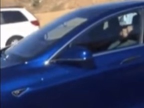 A still image of a driver on an L.A. highway sleeping behind the wheel of his Tesla, as its safety sensors apparently took over. (YouTube/Screengrab)