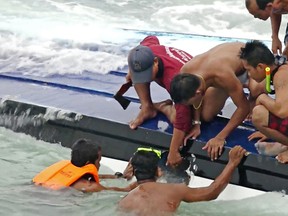 In this May 26, 2016, photo taken from video, rescue workers smash a hole in a capsized boat to retrieve a woman on Koh Samui, Thailand. Officials say a speed boat carrying 32 tourists and four crew members to the tourist resort island of Koh Samui capsized, leaving two foreigners dead and two others missing. (AP Photo)