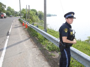 OPP Const. Christine Quenneville keeps watch over the scene on Highway 33 where a car went off The road and into the lake early this morning. Elliot Ferguson/The Whig-Standard