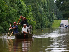 Roland Courville steers a boat across Mill Creek Road as he helps people escape from a neighborhood cut off by a flooded Spring Creek, Friday, May 27, 2016, in Magnolia, Texas. (Michael Ciaglo/Houston Chronicle via AP)