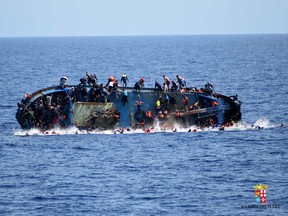 In this May 25, 2016 file photo made available by the Italian Navy, people try to jump in the water right before their boat overturns off the Libyan coast.  (Italian navy via AP Photo, file)