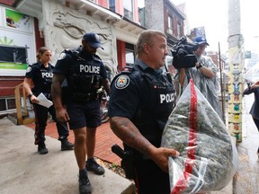 Police officers carry out pot and other items last week during a raid on a pot dispensary in Kensington Market. (MICHAEL PEAKE, Toronto Sun)