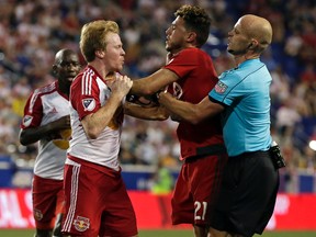 Red Bulls’ Dax McCarty (left) and TFC’s Jonathan Osorio exchange pleasantries while being restrained by referee Allen Chapman during their MLS match on Saturday. The Reds desperately need an unsung player such as Osorio to step up. (AP/PHOTO)