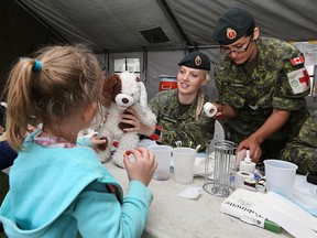 Kate Koschik has her teddy Splash returned by Cpl. Jana Goodmanson in the 17 Winnipeg Field Ambulance MASH tent at the 30th annual Teddy Bears' Picnic, presented by the Children's Hospital Foundation of Winnipeg, at Assiniboine Park on Sun., May 29, 2016. (Kevin King/Winnipeg Sun/Postmedia Network)