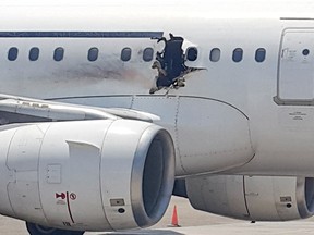 In this Tuesday, Feb. 2, 2016 file photo, of a  hole in a plane operated by Daallo Airlines as it sits on the runway of the airport in Mogadishu, Somalia. A military court in the Somali capital has given life terms Monday, May 30, 2016 to two men convicted of masterminding the bombing in February of the airliner which made an emergency landing with a gaping hole in its fuselage. (AP Photo, File)