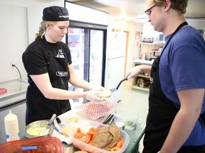 Summer students Elena Moffatt and Keegan Tansey works in The Back Kitchen in Stella on Amherst Island on Thursday. The restaurant reopened as a volunteer-based project. (Elliot Ferguson/The Whig-Standard)