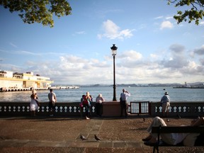 In this Nov. 23, 2011, file photo, tourists look out from the pier near the cruise ship terminal in Old San Juan, Puerto Rico. The island has been hit harder by Zika than any other part of the U.S., with more than 1,170 confirmed cases, one death and the first microcephaly case acquired on U.S. soil.  (AP Photo/Ricardo Arduengo, File)