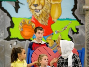 Aliyah Daher, (L-grade 2), Audrey Vallieres (middle-senior kindergarten), and Jumanah Basher (R-grade 6) and Jacob Pieschke (top-grade 5) hang out on the Friendship Bench at E'cole elementaire publique Des Sentiers in Orleans on Wednesday May 11, 2016. Des Sentiers is the first French school in North America to own it's buddy bench from the Kill It With Kindness, a grass roots anti-bullying organization. Errol McGihon