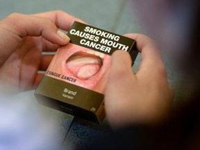 Local Ottawa high school students look at plain cigarette packaging examples, on World No Tobacco Day, prior to meeting with Minister of Health Jane Philpott in Ottawa on Tuesday, May 31, 2016. Philpott officially launched public consultations on plain packaging requirements for tobacco products. THE CANADIAN PRESS/Sean Kilpatrick