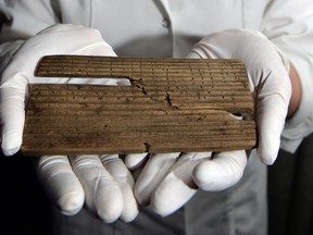 Luisa Duarte, a conservator for the Museum of London, holds a piece of wood with the Roman alphabet written on it, in London, on June 1, 2016. Archaeologists say they have discovered the oldest handwritten document ever found in Britain among hundreds of 2,000-year-old waxed tablets from Roman London. (John Stillwell/PA via AP)