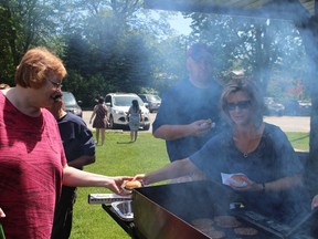 High school teachers fired up the grill at Southside Park on Wednesday, June 1, 2016 during a co-op appreciation barbecue to recognize the local employers that supported co-op students this year. Maureen Janssen, whose son is a co-op student, accepted a burger from St. Mary's teacher Michelle Burrell. (MEGAN STACEY/Sentinel-Review)