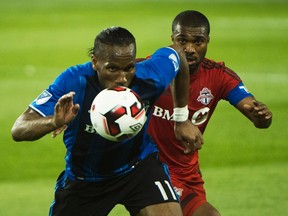 Montreal Impact forward Didier Drogba keeps his eyes on the ball with Toronto FC defender Ashtone Morgan in pursuit during last night’s game. (THE CANADIAN PRESS)