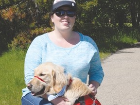 Aleigha Kravontka kneels with her son Ryley’s dog guide, Henry, during the Walk for Dog Guides. The golden retriever is specially trained to assist Ryley with his autism. - Photo by Marcia Love