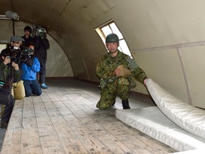 A member of the Self-Defence Forces shows the mattress which the 7-year-old Japanese boy who went missing nearly a week ago, was using inside a building in a military drill area in Shikabe town, on the northernmost main island of Hokkaido Friday, June 3, 2016. The boy, missing since Saturday, was found unharmed Friday, police said, in a case that had set off a nationwide debate about parental disciplining.  (Risa Ominato/Kyodo News via AP)