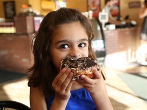 Nova Gregorini, 6, sinks her teeth into a donut at Mighty Canadian Doughnuts on Barrydowne Road in Sudbury, Ont. on Thursday June 2, 2016. John Lappa/Sudbury Star/Postmedia Network