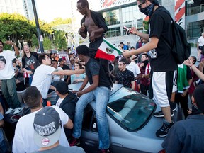 Protesters against Republican presidential candidate Donald Trump climb on a car outside a Trump campaign rally on Thursday, June 2, 2016, in San Jose, Calif. A group of protesters attacked Trump supporters who were leaving the candidate's rally in San Jose on Thursday night. A dozen or more people were punched, at least one person was pelted with an egg and Trump hats grabbed from supporters were set on fire on the ground. (AP Photo/Noah Berger)