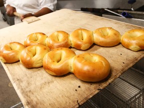 Baker Sharelle Robbins removes a pastry mat laden with egg bagels fresh from the oven at Kossar's Bagels and Bialys in New York on Thursday, May 26, 2016. At street carts and bodegas, diners and supermarkets, nowhere is the bagel more ubiquitous than New York City. (AP Photo/Kathy Willens)