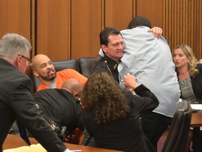 A court officer tackles the father of one of three victims of Ohio serial killer Michael Madison, left, who leaped over a table to attack the defendant in court just minutes after the judge pronounced a death sentence in Cuyahoga County Common Pleas Court on June 2, 2016, in Cleveland. (AP Photo/David Richard)