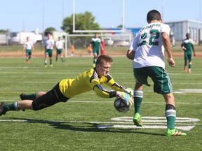 Cameron Heights Collegiate Institute's goalkeeper Damian Kruschat dives on the ball in front of Holy Cross's Antonino D'Amore during the Crusaders' 2-1 win Friday at the Ontario Federation of School Athletic Association senior boys AAA soccer championship. (Elliot Ferguson/The Whig-Standard)