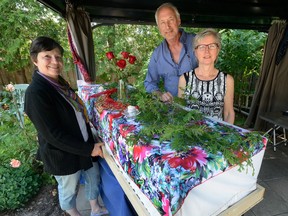 Janet Sparey, Don Morris, and Shannon Calvert, l-r, are pictured beside a cardboard casket in Calvert's back yard where they will hold a seminar on how to have a home funeral. (MORRIS LAMONT, The London Free Press)