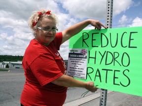 Sharon Chartrand posts a sign on Municipal Road 24 in Lively at a Hydro One - Enough is Enough event to protest high hydro prices. Ben Leeson/The Sudbury Star/Postmedia Network