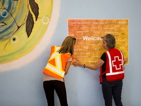 Sarah Thomas from the Regional Municipality of Wood Buffalo and Becky Row with the Red Cross hang a welcome sign as they get ready to open the door at the Nistawoyou Association Friendship Centre on June, 3 2016 in Fort McMurray . Postmedia, Wildfires(Greg Southam-Postmedia)