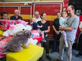Christopher and Michele Bergevin — along with their kids, Elsie, 4, and Bowman, 1, — smile after receiving a cheque for $1,000 from the Toronto Professional Fire Fighters’ Association. (ERNEST DOROSZUK, Toronto Sun)