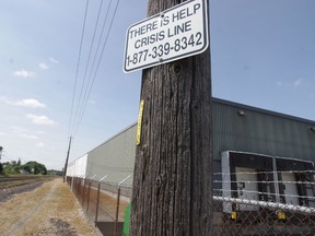 This file photo shows a sign at railway tracks in Woodstock, Ont., offering a toll-free number for the Canadian Mental Health Association's crisis line for those contemplating suicide. (HEATHER RIVERS/Woodstock Sentinel-Review/Postmedia Network Files)