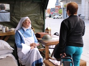 Barbara Monk, dressed in a First World War nurse outfit, greets visitors at the D-Day display in Springer Market Square on Monday. (Julia Balakrishnan/For The Whig-Standard)