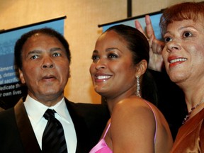 In this Feb. 26, 2005, file photo, former heavyweight boxing champion Muhammad Ali, left, jokingly holds up two fingers behind the head of his daughter, Laila Ali, as they and his wife, Lonnie Ali, pose for cameras during a news conference before a tribute to him coinciding with Black History Month in Atlanta. (AP Photo/John Amis, File)