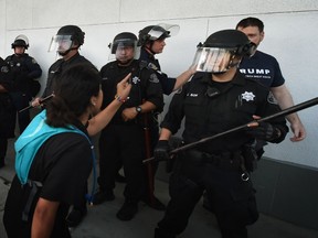 Police protect a Trump supporter (R) as protesters demonstrate outside the convention centre where Republican presidential candidate Donald Trump held an election rally in San Jose, California on June 2, 2016. (AFP PHOTO/Mark Ralston)
