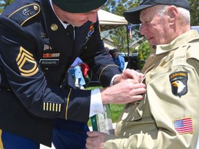 In this Saturday, June 4, 2016 photo, U.S. Army Sgt. First Class Russell Rodgers pins a Purple Heart on his 92-year-old grandfather PFC Russell S. Rodgers, more than 70 years after the World War II veteran fought in the Battle of the Bulge, at Brookdale Senior Living in Gardnerville about 45 miles south of Reno. (Brad Coman/The Record Courier via AP)