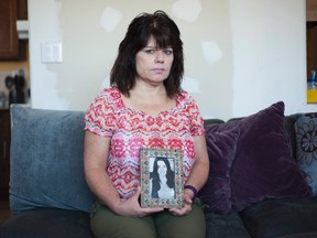 Janine Stearne holds up a photo of her oldest sister Donna Lee Stearne. her home in Waterloo, Ont. on Wednesday, April 27, 2016. Stearne's oldest sister, Donna Lee Stearne, was murdered in 1973 in Toronto and the case is still unsolved. (Hannah Yoon/The Canadian Press)