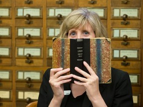 London Public Library librarian Joanna Kerr, who helps information seekers through the Book A Librarian program, holds the first city directory in The London Room at the central branch on Dundas Street in London, Ont. on Monday June 6, 2016. Craig Glover/The London Free Press/Postmedia Network