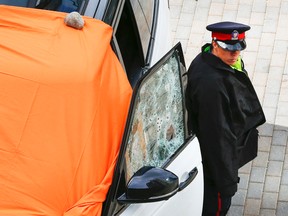 A Toronto Police officer stands guard beside a white Range Rover with at least 14 bullet holes through the driver's window in Cowbell Lane June 7, 2016. A man was killed. (Jack Boland/Toronto Sun)