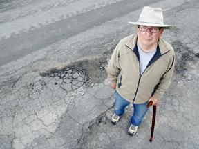 Luke Hendry/The Intelligencer
Mac Ellis holds his cane while standing on the rough asphalt outside his Karl Street home in Belleville. He said he's concerned the for the safety of seniors who walk the street, which in some places has an uneven surface and broken pavement.