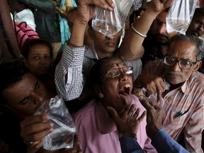 A member of the Goud family administers "fish medicine" to an asthma patient in Hyderabad, India, Wednesday, June 8, 2016. Started by the Bathini Goud family, the therapy is a secret formula of herbs, handed down by generations only to family members. The herbs are inserted in the mouth of a live sardine, or murrel fish, and slipped into the patient's throat. (AP Photo/Mahesh Kumar A.)