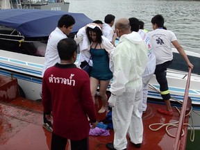 In this image made from video, a passenger is assisted from a police rescue boat at a pier in Phuket, Thailand, on June 8, 2016. Police say two speedboats carrying 62 tourists have collided off the coast of southern Thailand, leaving a number injured. (AP Photo)