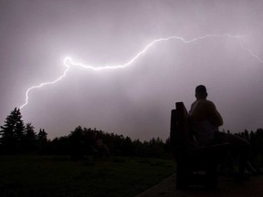 A man sits on a bench and watches the lightning near Saskatchewan Drive and 119 Street, in Edmonton Alta. on Monday June 6, 2016. Photo by David Bloom