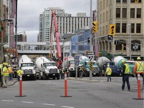 Pedestrians and news crews were clamouring into the early evening to catch glimpses of the sinkhole that opened up this morning just east of the intersection of Rideau Street and Sussex Drive, which caused a gas leak and building evacuations, on June 8, 2016. Cement trucks were just beginning to fill the hole around 6 p.m. (David Kawai)