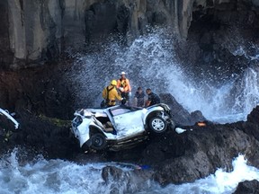 In this May 29, 2016 photo provided by Tom Johnson, rescue workers respond to the scene of a car crash off Maui’s Hana Highway in Hana, Hawaii. (Tom Johnson via AP)