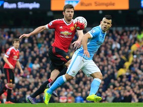 United’s Michael Carrick, left, and Manchester City's Sergio Aguero challenge for the ball during the English Premier League soccer match between Manchester City and Manchester United at the Etihad stadium in Manchester, Sunday, March 20, 2016. (AP Photo/Jon Super)