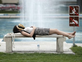 A woman has a rest on a bench near the fountain in Memorial Park. (FILE PHOTO)