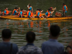 Spectators watch as dragon boats race across a lake during Duanwu Festival celebrations at Taoranting Park in Beijing on June 9, 2016. Chinese authorities say eight people are missing and 10 confirmed dead in a pair of recent boating disasters. (AP Photo/Mark Schiefelbein)