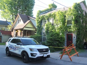 Police keep watch over a house on Ordnance Street in Kingston on June 10 after discovering a deceased man inside. A female family member was charged by police. (Michael Lea/The Whig-Standard)