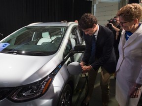 Prime Minister Justin Trudeau, left, and Ontario Premier Kathleen Wynne pose as they plug in a 2017 Chevrolet Volt electric vehicle before making an announcement at the General Motors plant in Oshawa, Ont., on Friday, June 10, 2016. THE CANADIAN PRESS/Chris Young