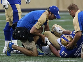 Winnipeg Blue Bombers C Jeff Keeping clutches his knee as he's attended to be training staff after being injured during Wednesday's game against Montreal. (Kevin King/Winnipeg Sun file photo)